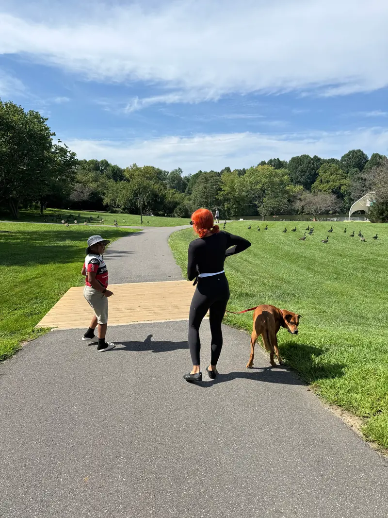 Moriah walking a dog with her son on a park path
