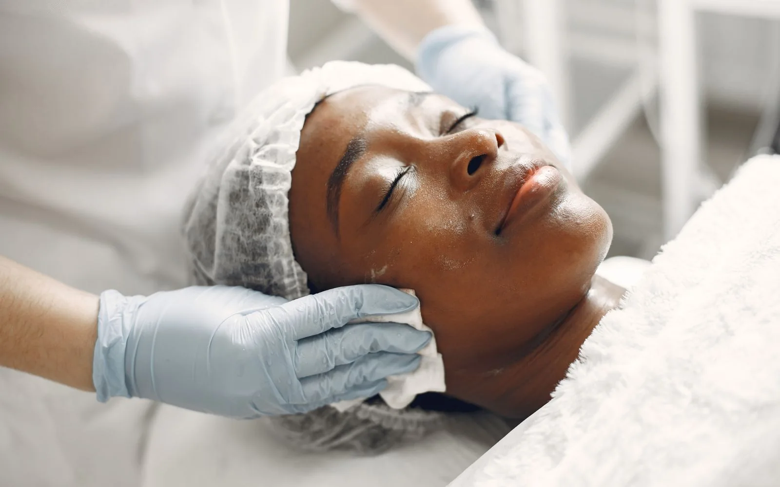 An esthetician providing a facial in a bright treatment room