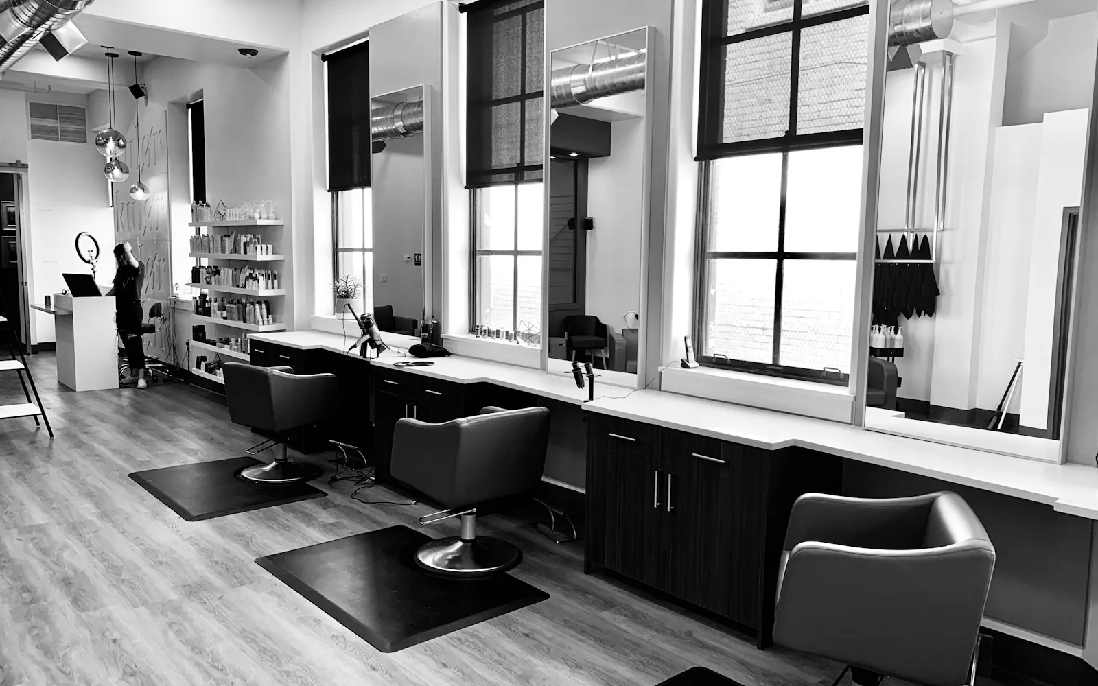 Sunlit salon styling stations with tall mirrors and black chairs